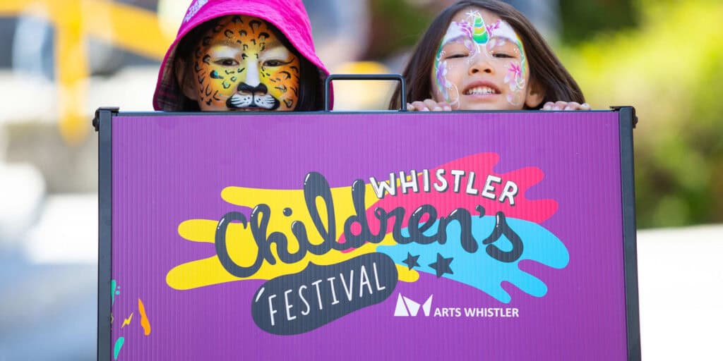 Two Kids peer over a sign at the Whistler Children's Festival