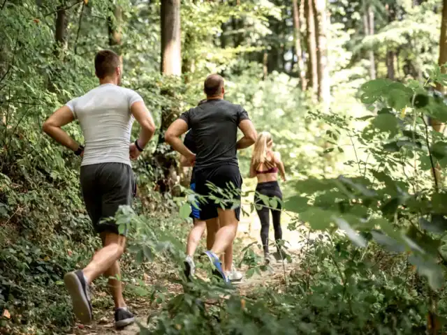 Three Friends Running in Forested Trails